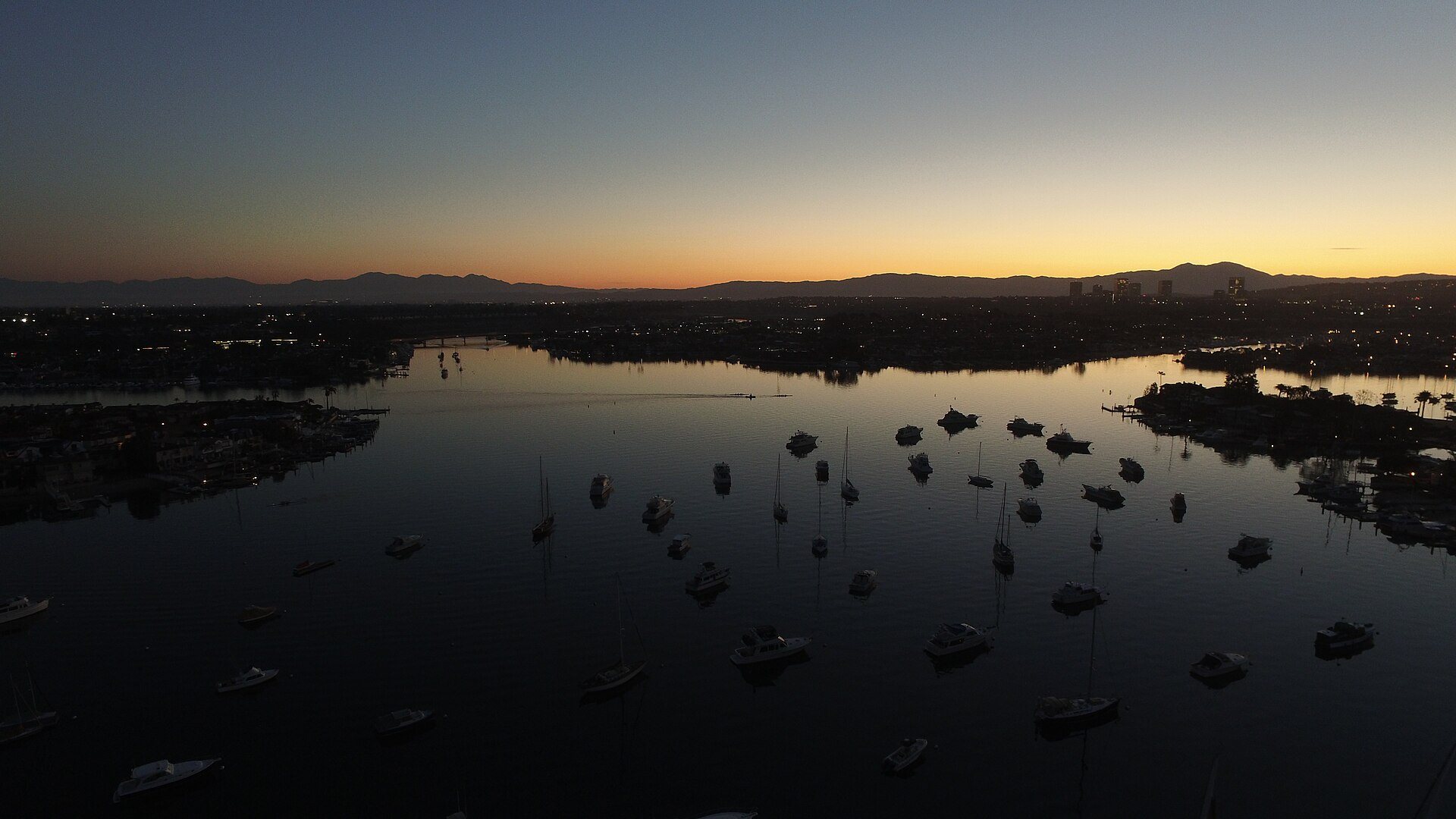 Newport Harbor at sunrise with moored boats and the Saddleback ridge
